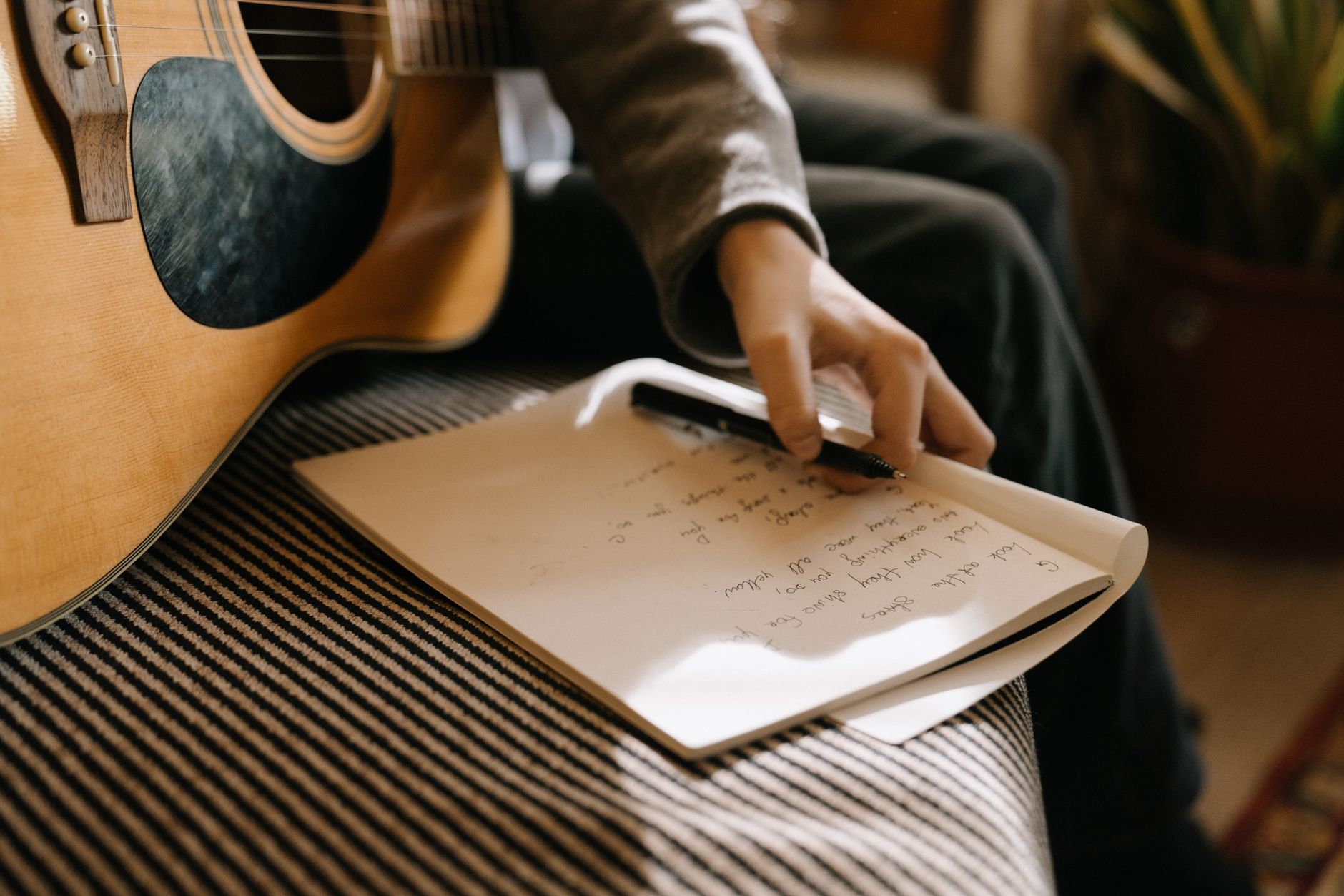 Songwriters collaborating around an acoustic guitar in a writing room