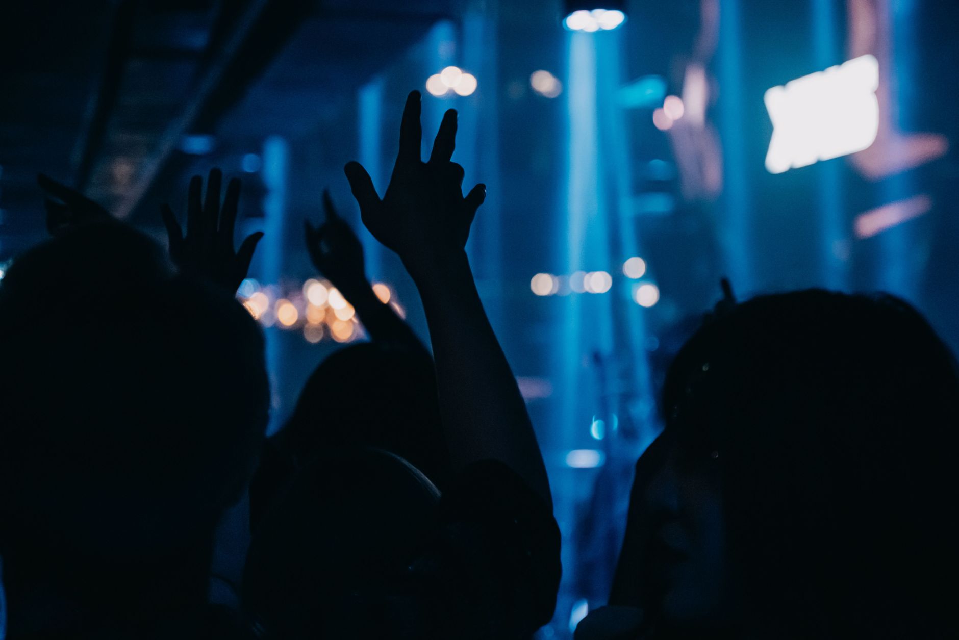 Stage lighting rig with moving lights above an arena crowd